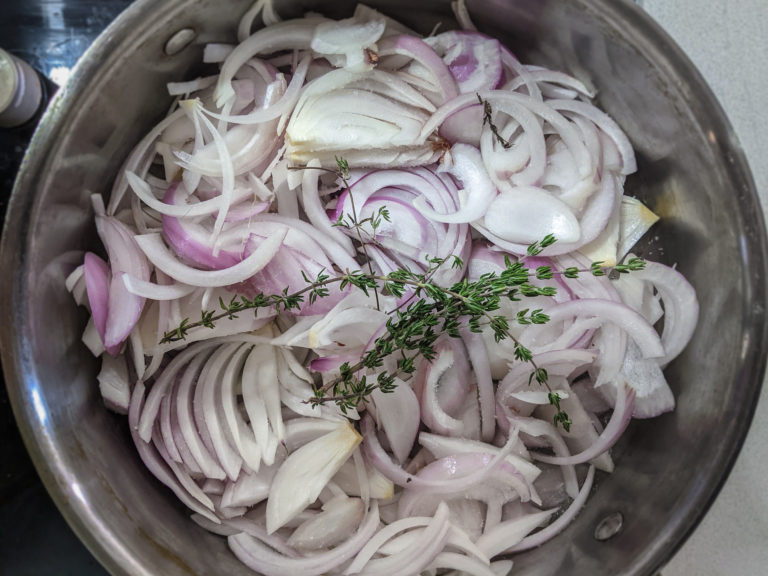 Sliced onions in a pan with thyme